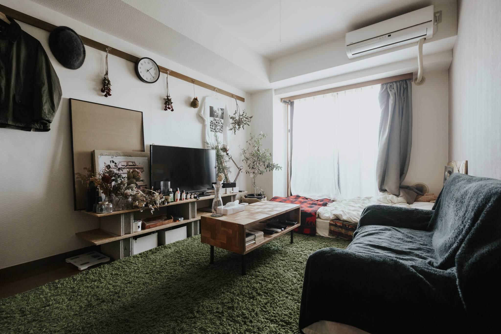 中富さんのお部屋は、低いベッドに対して大きめソファを直角に配置。ソファに座ったときに視界に入るテレビボードに好きなものを凝縮しています。