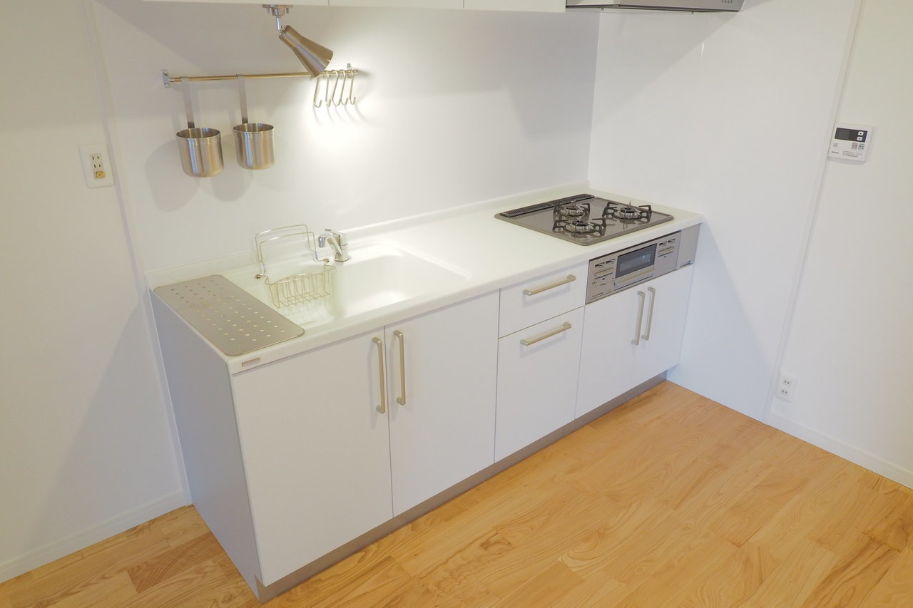 白色のキッチンには、3口ガスコンロとグリル付き。朝食や夕食など、忙しいときに手際よくコンロやスペースを使いこなす姿が目に浮かびます。（※写真はイメージです）