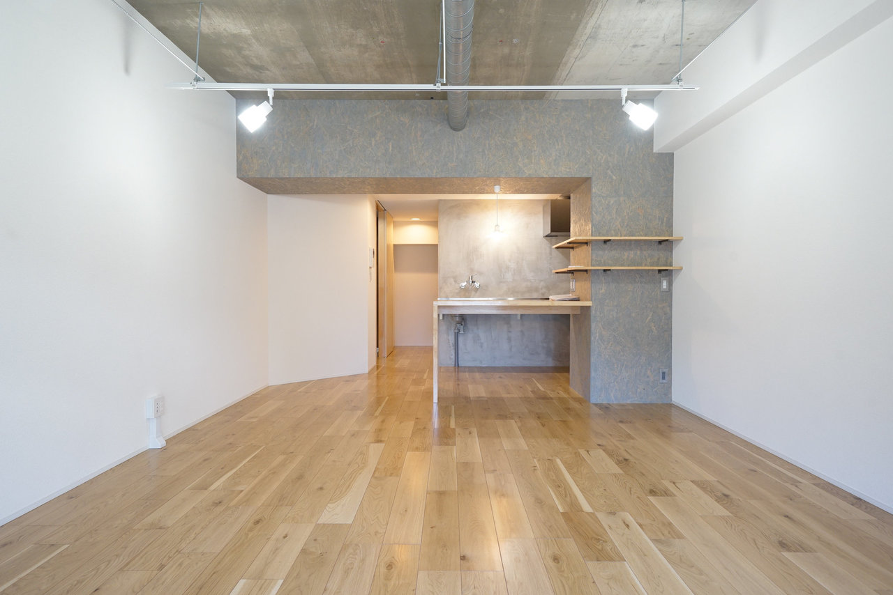 12畳の広々としたワンルーム。コンクリート打ちっぱなしの天井に、木材の温もりが感じられる無垢床。洗練された印象を感じるお部屋です。