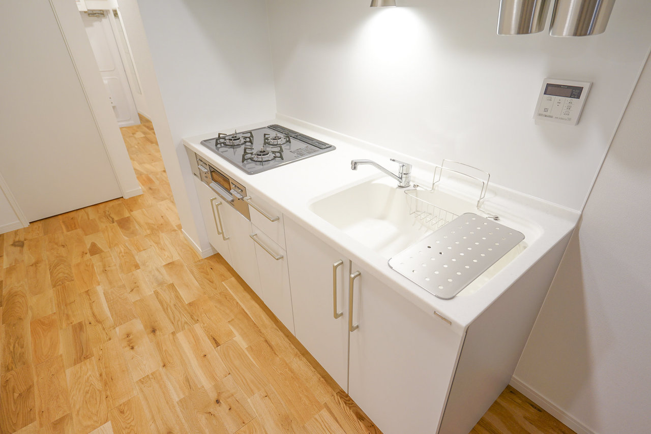 人工大理石の真っ白なキッチン天板。平で料理がしやすく、手入れも楽。デザイン的にもインテリアの邪魔をしません。