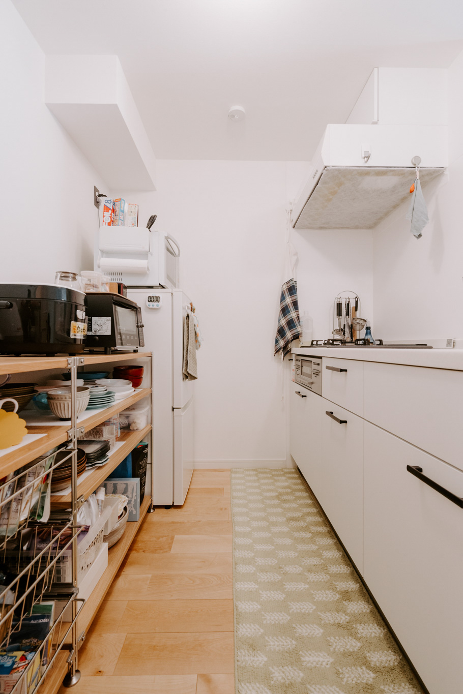 goodroomのオリジナルリノベーション「TOMOS」で暮らす方のお部屋。システムキッチンの背面は十分なスペースがあったため、無印良品のユニットシェルフを並べて使用しています。腰ほどまでの高さに揃えることで、炊飯器などの家電も使用しやすいようにしていらっしゃいました。