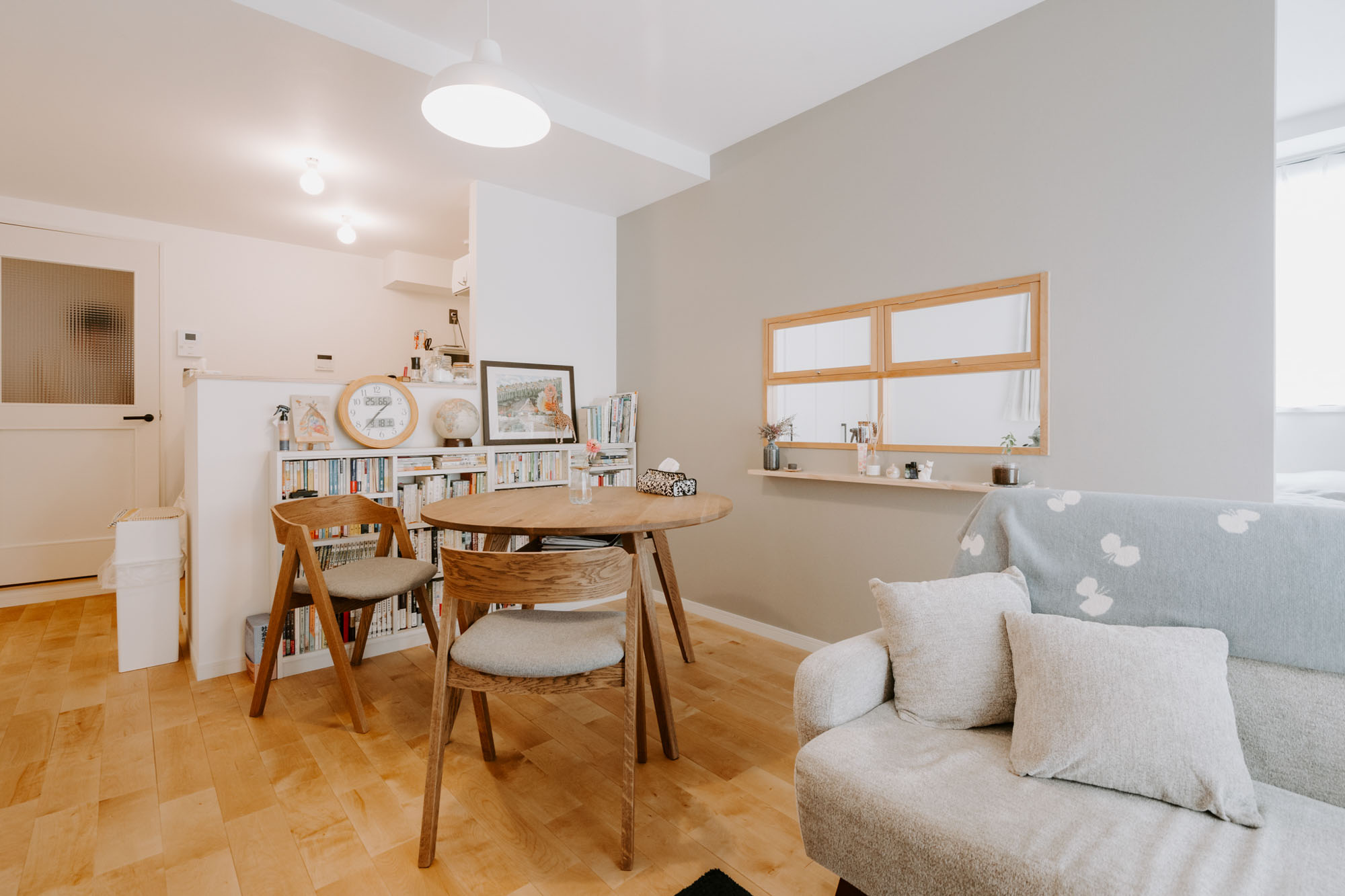 LDKには対面式のキッチンがあり、丸い木のダイニングテーブル、壁と同じグレーのソファを置いて、やわらかい雰囲気を作られています。