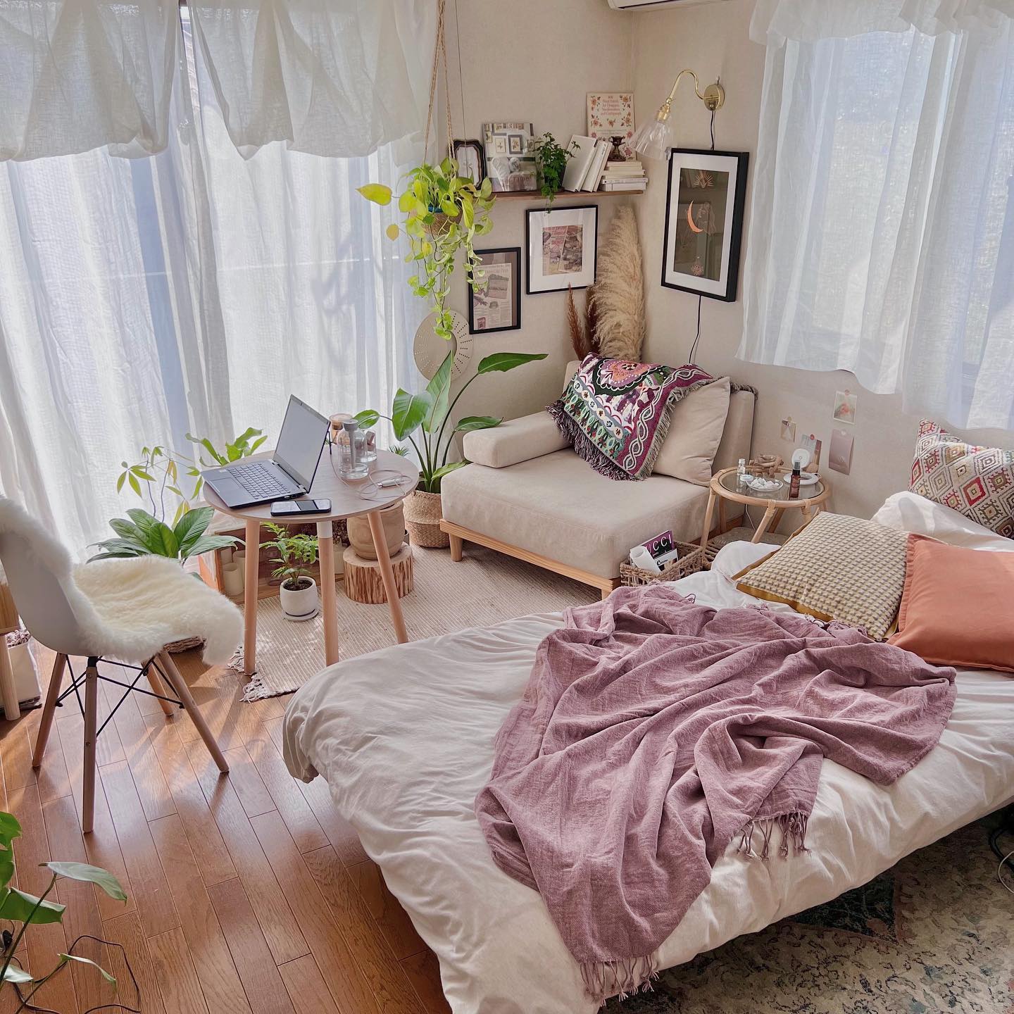 お部屋の広さは8.5畳ほど。手前にベッド、奥に一人がけのソファとリモートワーク用のデスク＆チェア、そして窓辺にたくさんの植物を配置されています。