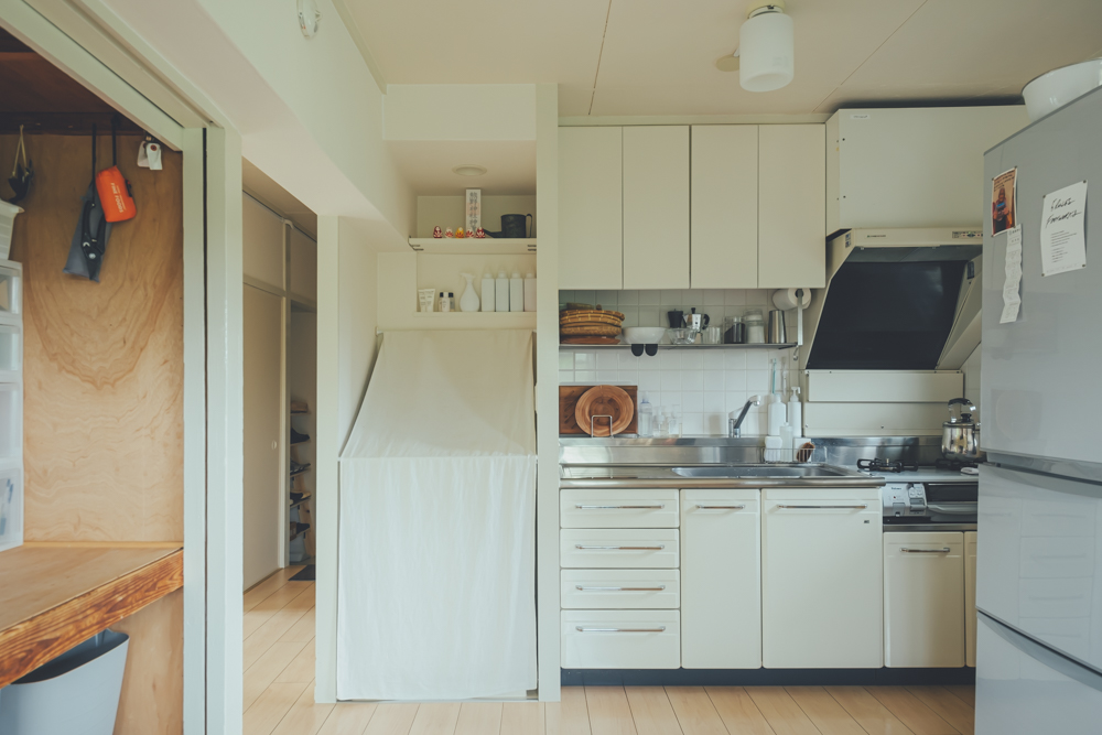 キッチンと、その隣にあるランドリースペースもすっきり。洗濯機は布で隠し、洗剤などは白の容器にきっちり移し替えをされていることもポイントです。